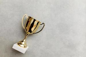 Simply flat lay design winner or champion gold trophy cup on concrete stone grey background. Victory first place of competition. Winning or success concept. Top view copy space. photo