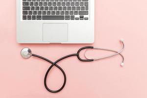 Stethoscope keyboard laptop computer isolated on pink background. Modern medical Information technology and sofware advances concept. Computer and gadget diagnostics and repair photo