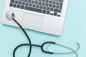 Stethoscope keyboard laptop computer isolated on blue background. Modern medical Information technology and sofware advances concept. Computer and gadget diagnostics and repair photo