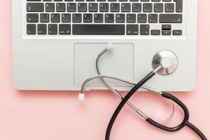 Stethoscope keyboard laptop computer isolated on pink background. Modern medical Information technology and sofware advances concept. Computer and gadget diagnostics and repair photo