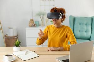 africano americano joven mujer vistiendo utilizando virtual realidad metaverso vr lentes auriculares a hogar. niña conmovedor aire durante vr experiencia en virtual realidad casco. simulación de alta tecnología videojuego concepto. foto