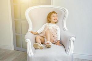 Little girl sitting on modern chair photo