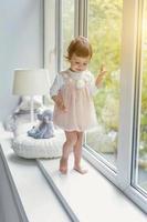 Little girl standing on window sill photo