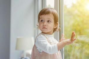 Little girl standing on window sill photo