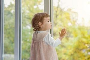 Little girl standing on window sill photo