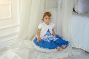 linda pequeño niña jugando en ligero blanco dormitorio foto