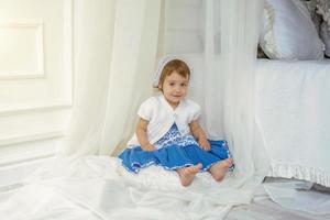 Cute little girl playing in light white bedroom photo