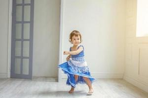 Little girl dancing in bright light living room at home and laughing photo