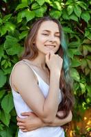 hermosa joven hipster brunete niña con largo verde pelo sonriente en parque antecedentes foto