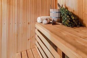 Traditional old Russian bathhouse SPA Concept. Interior details Finnish sauna steam room with traditional sauna accessories set basin birch broom towel aroma oil. Relax country village bath concept. photo