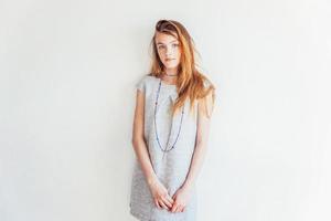 Beauty teenage girl. Portrait young teen woman in grey dress against white wall background. European woman. photo