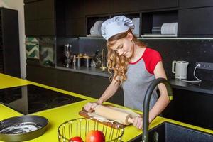 Teenage girl preparing dough, bake homemade holiday apple pie in kitchen photo