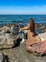 Woman with long hair is standing on seashore dressed photo