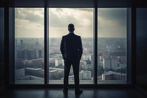 A businessman seen from behind is looking out of an office window in the big city created with technology. photo