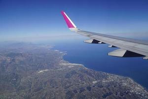 Flying over Coast of Spain - plane wing and Mediterranean Sea photo