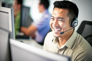 The Chinese man is smiling, sitting at his desk wearing a headset. Working in a call center. . photo