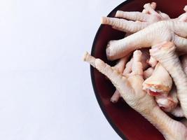 Raw fresh chicken feet in a bowl isolated on white background photo