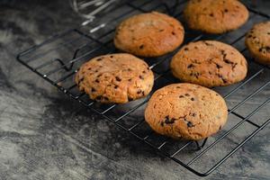 Homemade chocolate chip cookies on black baking cooling tray and abstract background photo