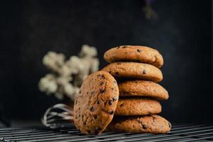 Homemade chocolate chip cookies on black baking cooling tray and abstract background photo