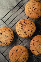 Homemade chocolate chip cookies on black baking cooling tray and abstract background photo