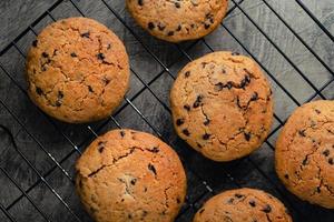 Homemade chocolate chip cookies on black baking cooling tray and abstract background photo