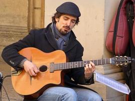 Bologna, Italy, April 16, 2022 Street performer playing acoustic guitar. Busking on street concept. photo