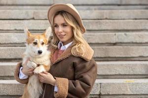 A young blonde woman in a hat on a walk in the park with Welsh Corgi-Pembroke dogs.Spring photo