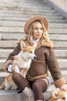 A young blonde woman in a hat on a walk in the park with Welsh Corgi-Pembroke dogs.Spring photo