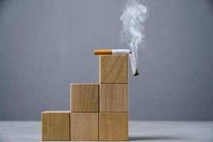 Top wooden ladder of cubes lies a broken, smoking cigarette.Concept World No Tobacco Day. photo