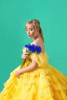 Beautiful young blonde caucasian woman in yellow dress with blue cornflower on green background. Fashion, Ukraine, flowers, style concept photo