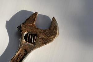 Dirty old wrench with hard shadow on white background photo