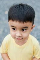 Portrait of an Asian boy wearing a yellow t-shirt. Blurred background. photo