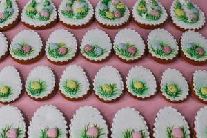 A pink table with decorated Easter cookies and decorated eggs. photo