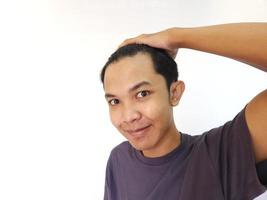 Shocked face of Asian man getting bald and lost hair in isolated white background photo