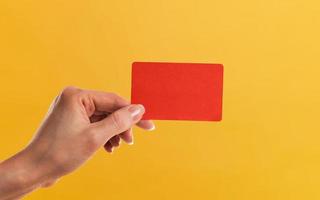 un mano participación un rojo tarjeta con un amarillo antecedentes. foto