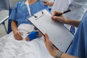 Injured patient showing doctor broken wrist and arm with bandage in hospital office or emergency room. Sprain, stress fracture or repetitive strain injury in hand. Nurse helping customer. First aid. photo