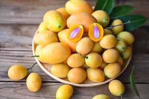 mariano ciruela Fruta y hojas en plato en de madera fondo, tropical Fruta nombre en Tailandia dulce amarillo mariano ciruela maprang plango o mayong chid foto