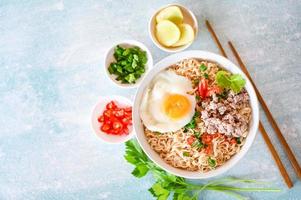 noodles bowl with boiled egg minced pork vegetable spring onion lemon lime lettuce celery and chili on table food, noodle soup instant noodles cooking tasty eating with plate photo