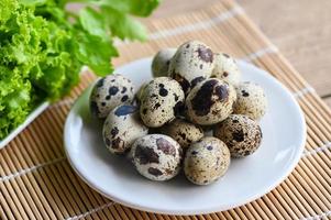 boiled eggs food, quail eggs on white plate, breakfast eggs with fresh quail eggs and vegetable coriander on wooden table background photo