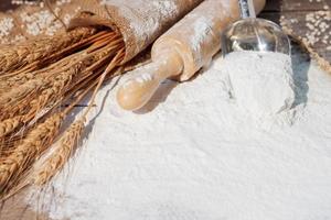 harina y orejas de trigo, cebada, cocinando, pan, y galletas fueron arreglado en el de madera mesa antecedentes en un rústico cocina. parte superior vista. foto