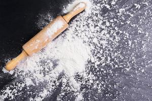 Heaps of wheat flour with ears of wheat on the table, black background - top view photo