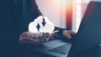 cloud computing concept, businessman working on computer laptop holding smartphone with cloud storage icon photo