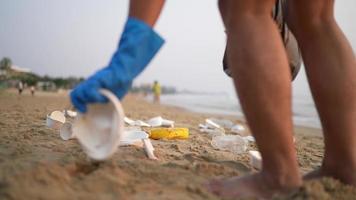 Zusammenarbeit Reinigung Plastik auf das Strand. Freiwillige sammeln Müll im ein Müll Tasche. Plastik Verschmutzung und Umwelt Problem Konzept. freiwillig Reinigung von Natur von Plastik. Begrünung das Planet video