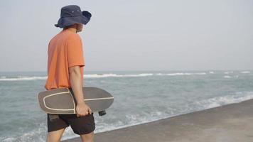 Mens wandelen met surfen skateboard in de buurt de zee video