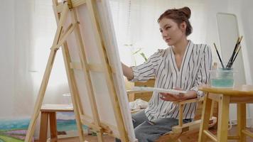 Professional female artist girl use paintbrush in abstract art for create masterpiece. painter paint with watercolors or oil in studio house. beautiful woman enjoy painting as hobby. work recreation video