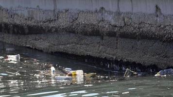 agua contaminación con sucio y el plastico basura flotante en el superficie de el mar video