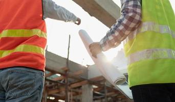 inspector or engineer is inspecting construction and quality assurance new house using a blue print. Engineer or architects or contactor work to build the house before handing it over to the homeowner photo
