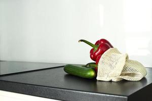 Vegetables in a grid on the kitchen table. Bulgarian pepper and cucumbers. Grid for vegetables. photo