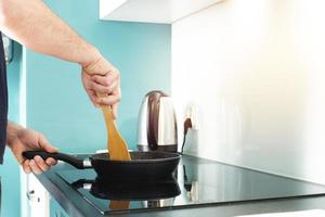 el hombre es Cocinando en el cocina. del hombre manos y fritura cacerola. fritura. foto