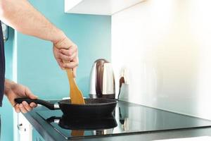 The man is cooking in the kitchen. Man's hands and frying pan. Frying. photo